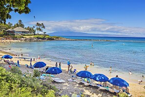 A beach with umbrellas, lounge chairs, and a clear view of the ocean.