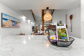 Un piano di lavoro in marmo con un cesto in filo nero contenente una confezione di caffè Maui e una ciotola decorativa.