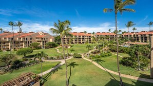 Un resort con varias construcciones, palmeras y césped bien cuidado.