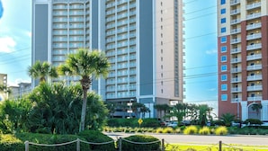 Un hôtel à plusieurs étages, doté de balcons, d’une tour centrale et d’un parking.