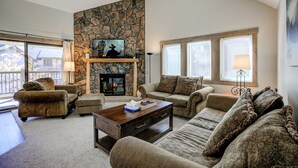 Un salón acogedor con chimenea de piedra, asientos cómodos y un amplio ventanal que proporciona luz natural.