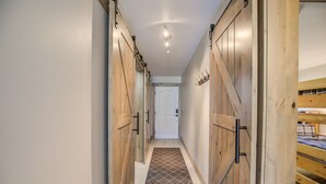 Un pasillo con puertas de madera y un tapete estampado que conduce a un dormitorio con literas.