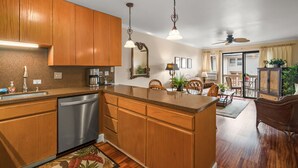 A modern kitchen with wooden cabinets, stainless steel appliances, and pendant lighting.