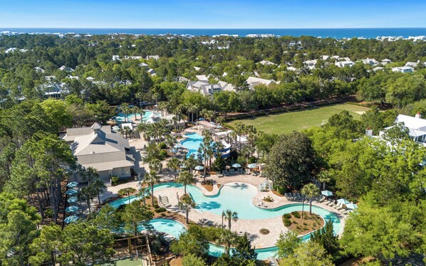 Um resort com uma grande área de piscina, vários edifícios e vista para o mar.