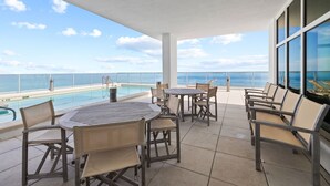 En tagterrasse med pool, udendørs møbler og havudsigt.