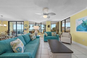 A spacious living room with a large teal sofa, a dark coffee table, and a ceiling fan.