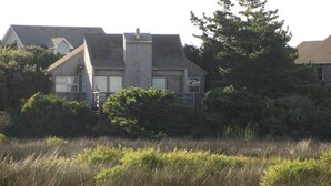 Une maison à deux étages avec une façade en pierre, une cheminée et un petit porche à l’avant.