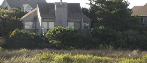 Una casa de dos pisos con fachada de piedra, una chimenea y un pequeño porche delantero.