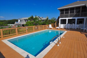 A wooden deck with a swimming pool, white lounge chairs, and a two-story building with a balcony. - Silver Creek: Semi-Oceanfront, Private Pool, Hot Tub (Southern Shores)