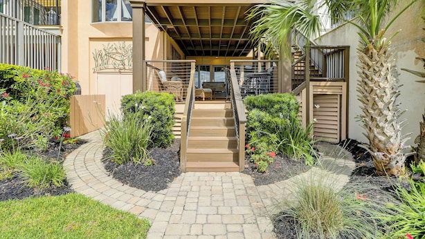 A residential building with a covered outdoor area, a staircase leading to a balcony, and a garden with various plants. - 17 Mizzenmast Ct - Amazing Views of 18th Fairway of Harbour Town Golf Links (Hilton Head Island)
