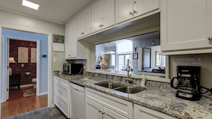 A modern kitchen with white cabinets, granite countertops, a stainless steel sink, and a coffee maker. - 17 Mizzenmast Ct - Amazing Views of 18th Fairway of Harbour Town Golf Links (Hilton Head Island)
