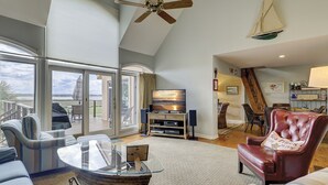 A spacious living room with a large glass table, comfortable seating, a television, and a sailboat decoration. - 17 Mizzenmast Ct - Amazing Views of 18th Fairway of Harbour Town Golf Links (Hilton Head Island)