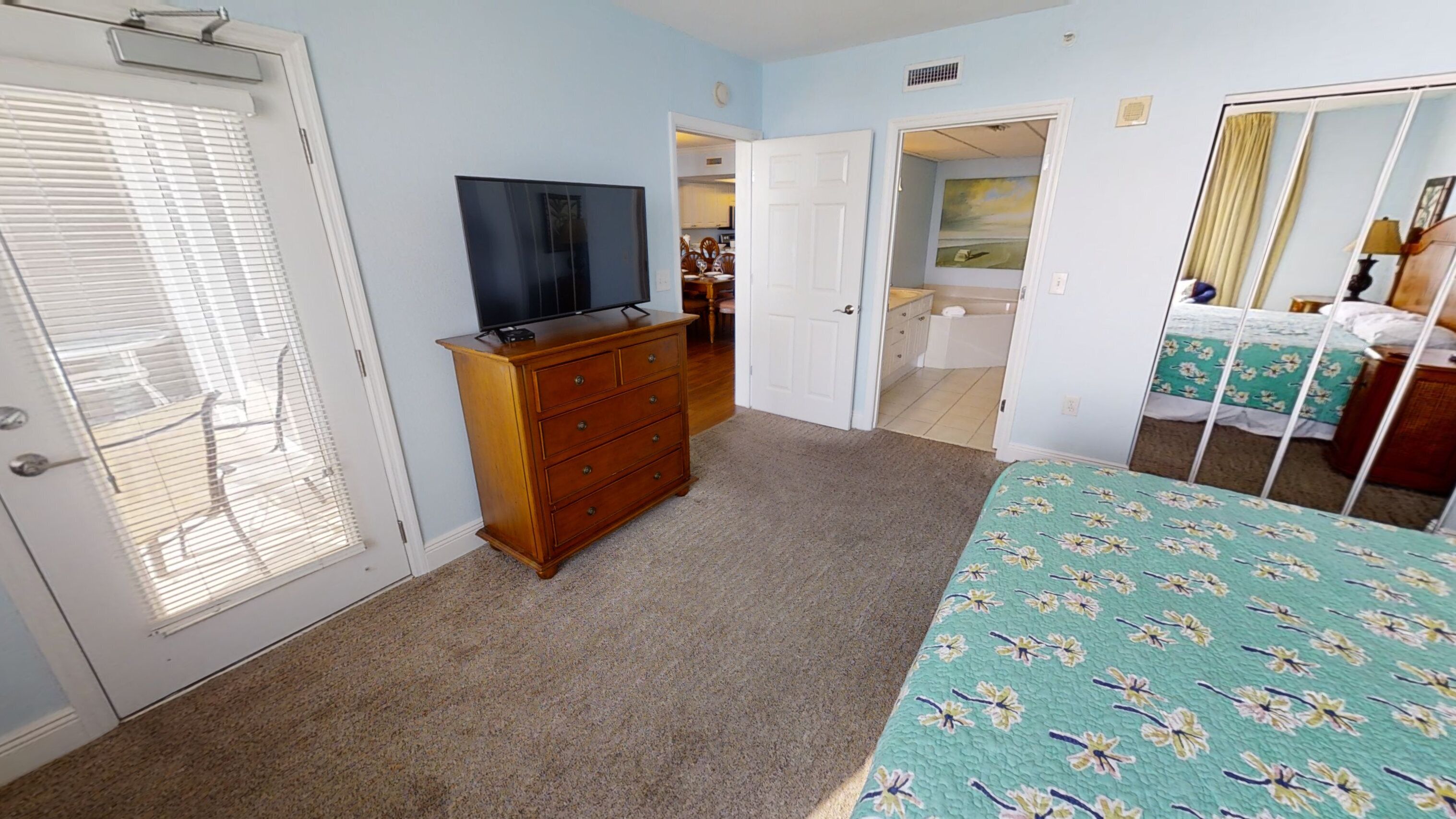 A bedroom with a bed, dresser, and a television.