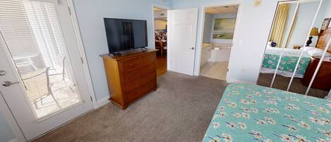A bedroom with a bed, dresser, and a television.