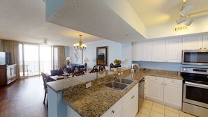 A modern kitchen with granite countertops, white cabinets, and stainless steel appliances. - Gulf Front Main Bedroom Free round of Golf & Activities Every Day! (Panama City Beach)