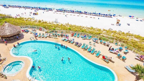 A resort with a large swimming pool, sun loungers, and a beach area. - Gulf Front Main Bedroom Free round of Golf & Activities Every Day! (Panama City Beach)