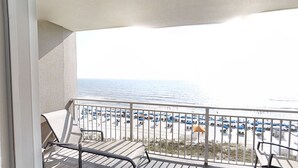 A balcony with a view of a beach with umbrellas and chairs. - Gulf Front Main Bedroom Free round of Golf & Activities Every Day! (Panama City Beach)