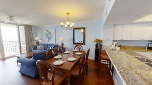 Ein geräumiges Wohnzimmer mit Essbereich, eine Küche mit weißen Schränken und ein Balkon mit Blick.