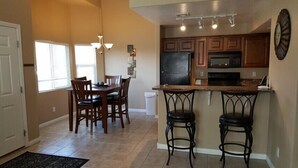 A kitchen with wooden cabinets, a refrigerator, an oven, and a bar area with stools. - Camellia Ridge by Mesquite Vacation Rentals with Community Amenities and $510 in free daily activities (Mesquite)