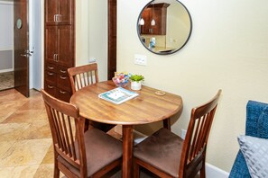 Een ronde houten eettafel met vier stoelen, een kleine potplant en een tijdschrift op tafel.