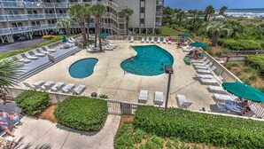 Ein Hotel mit Poolbereich, der zwei Pools, Liegestühle und Palmen umfasst.