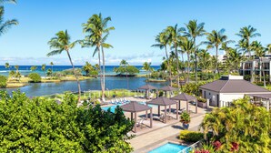 Un resort con piscina, palmeras y vista al océano.