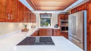 Una cocina moderna con armarios de madera, electrodomésticos de acero inoxidable y una isla central con estufa.