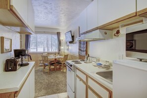A compact kitchen with a stove, sink, and a small dining area.