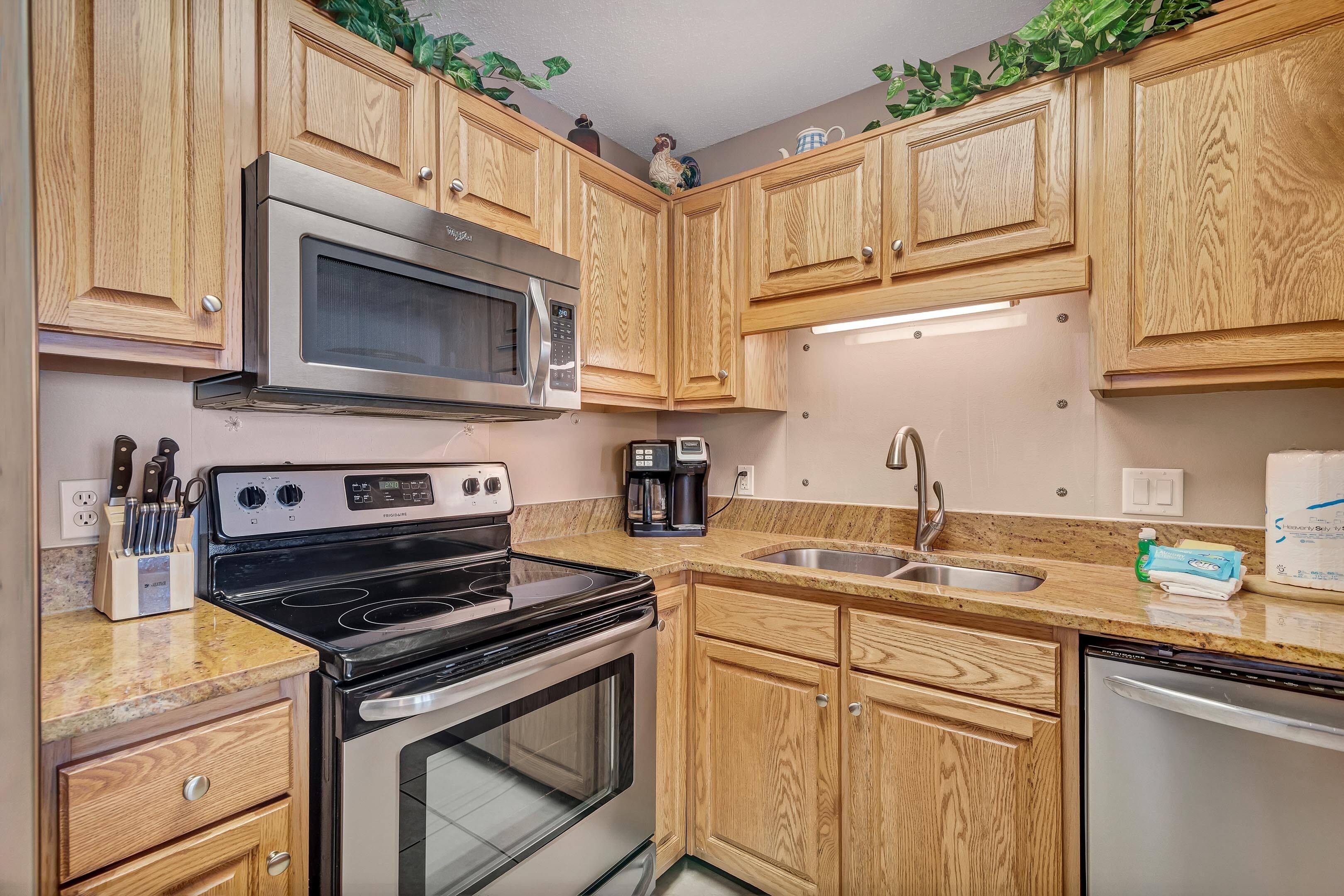 A kitchen with wooden cabinets, a stainless steel microwave, a stove, a coffee maker, and a dishwasher.