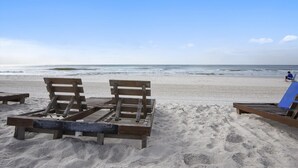 Una spiaggia con panchine di legno e una poltrona da relax blu.