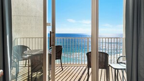 En balkon med udsigt over havet, med et bord og stole.