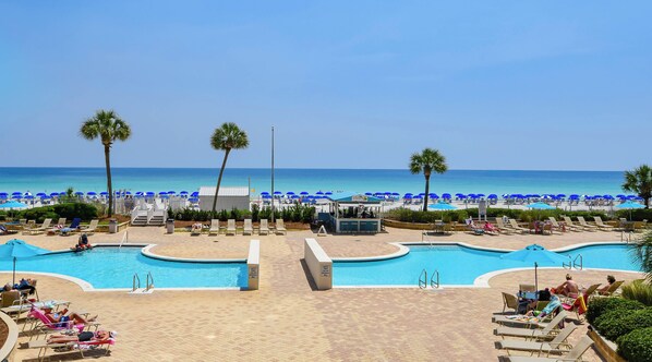 A pool area with lounge chairs and a beach in the background. - Modern beachfront condo w/ expansive private balcony in Destin! 💙 (Destin)