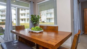 A dining area with a wooden table, chairs, and a plant centerpiece.