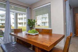 A dining area with a wooden table, chairs, and a plant centerpiece.