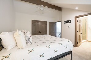 A bedroom with a bed, pillows, a ceiling fan, and a door leading to another room. - Elk Ridge Trail Townhome: Hot Tub, Spacious, Cool Location (Breckenridge)