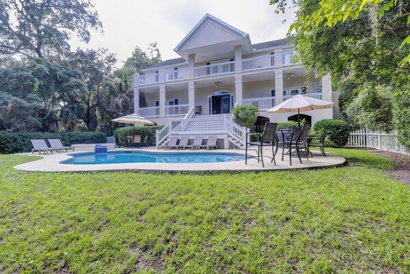 Une maison à deux étages avec une piscine, un espace extérieur aménagé pour se détendre et une terrasse couverte.