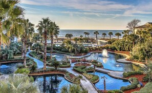 Un resort con diverse piscine, palme e vista sull'oceano.