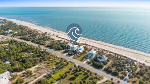 Aerial view showcasing a pristine beachfront community with turquoise waters and sandy shores stretching along the coastline. - Pelican Palms: 4 BR IP Beachfront Home- Sleeps 14, Pet Friendly, Priv. Pool! (Port St. Joe)