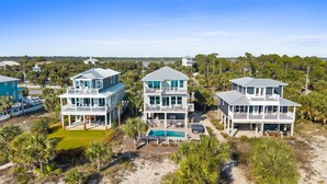 A beachfront property with three multi-story houses, each featuring balconies and a shared swimming pool.