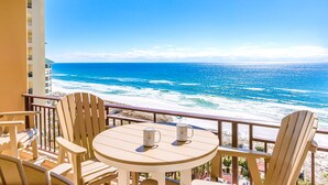 Een balkon met een tafel en stoelen met uitzicht op een strand en oceaan.
