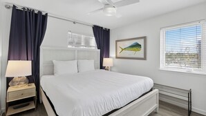 A bedroom with a bed, two bedside tables with lamps, a ceiling fan, a window with blinds, and a framed fish painting on the wall. - Gulf Front - Beach Chairs - Seagrove Beach! (Santa Rosa Beach)
