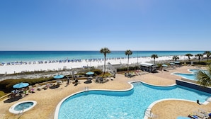 A resort with a swimming pool, beach, and clear blue sky.