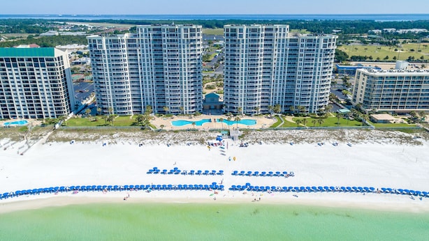 A high-rise hotel with multiple floors, a beachfront, and a pool area.