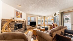 A cozy living room with a stone fireplace, a television, and comfortable seating.