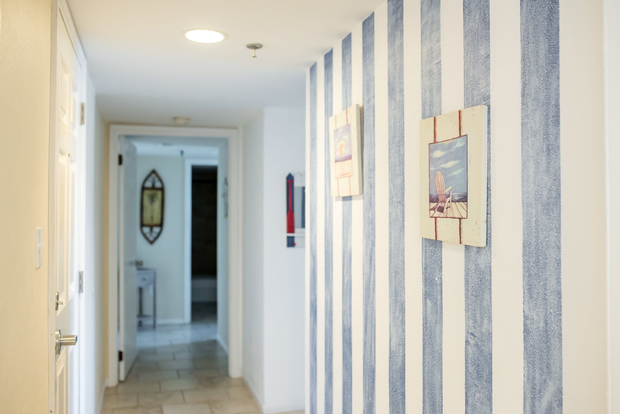 A hallway with striped wallpaper, a door on the left, and a framed picture on the right.