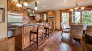 A spacious kitchen with wooden cabinets, a stainless steel refrigerator, and a large island with bar stools.