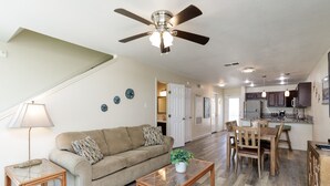 A spacious living room with a sofa, coffee table, and dining area. - Beachfront Condo | Stunning Views, Private Balconies & Pool (Corpus Christi)