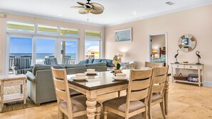 A spacious living area with a dining table set for four, a sofa, and a view of the ocean. - CASA DEL SOL - 4BR 4 BTH BEACHFRONT HOME W/POOL located in The Plantation (St, George Island)