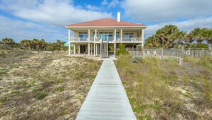 A two-story house with a covered porch and a wooden walkway leading to the entrance. - CASA DEL SOL - 4BR 4 BTH BEACHFRONT HOME W/POOL located in The Plantation (St, George Island)