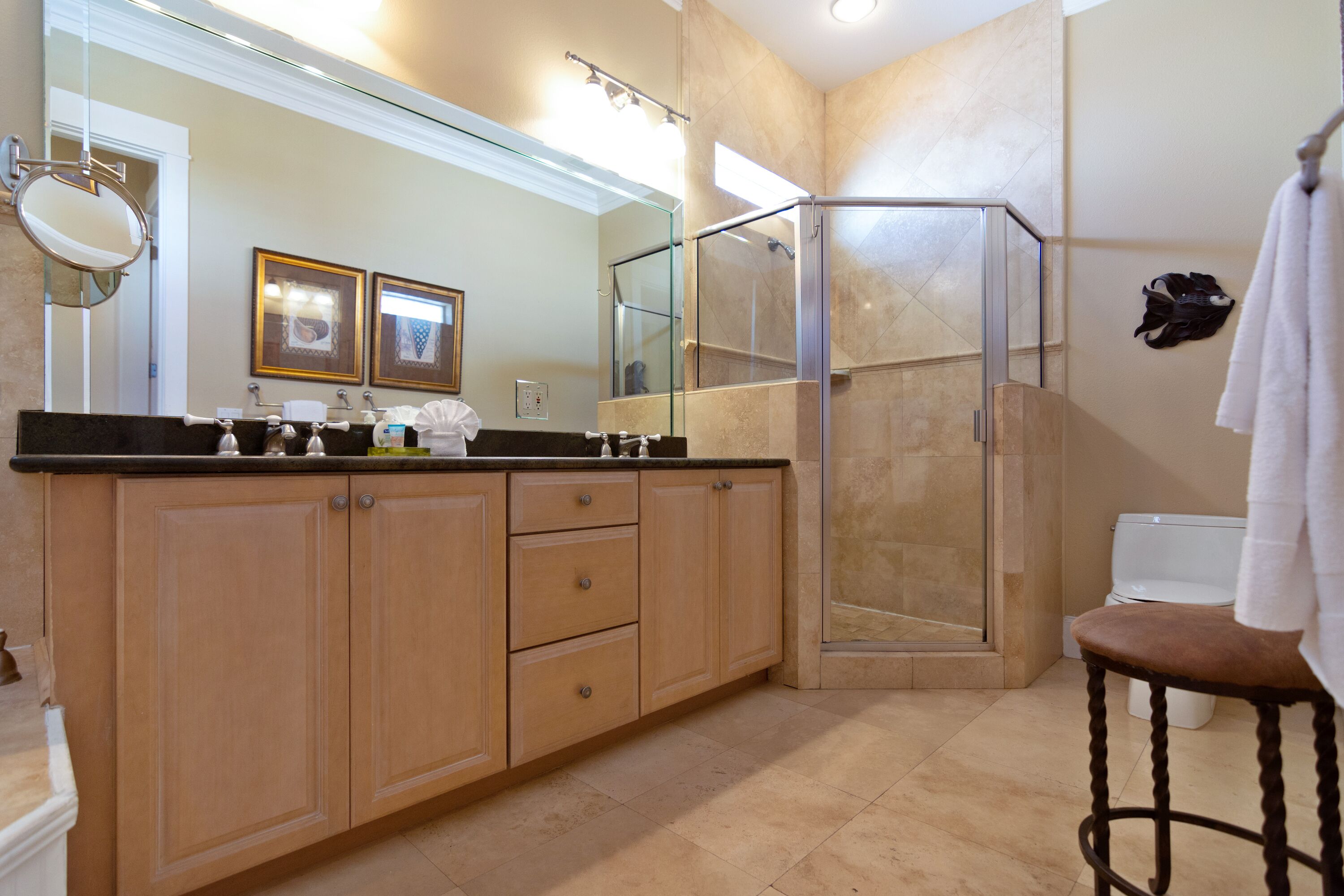 A modern bathroom with a large mirror, wooden cabinets, a glass shower enclosure, and a white toilet.